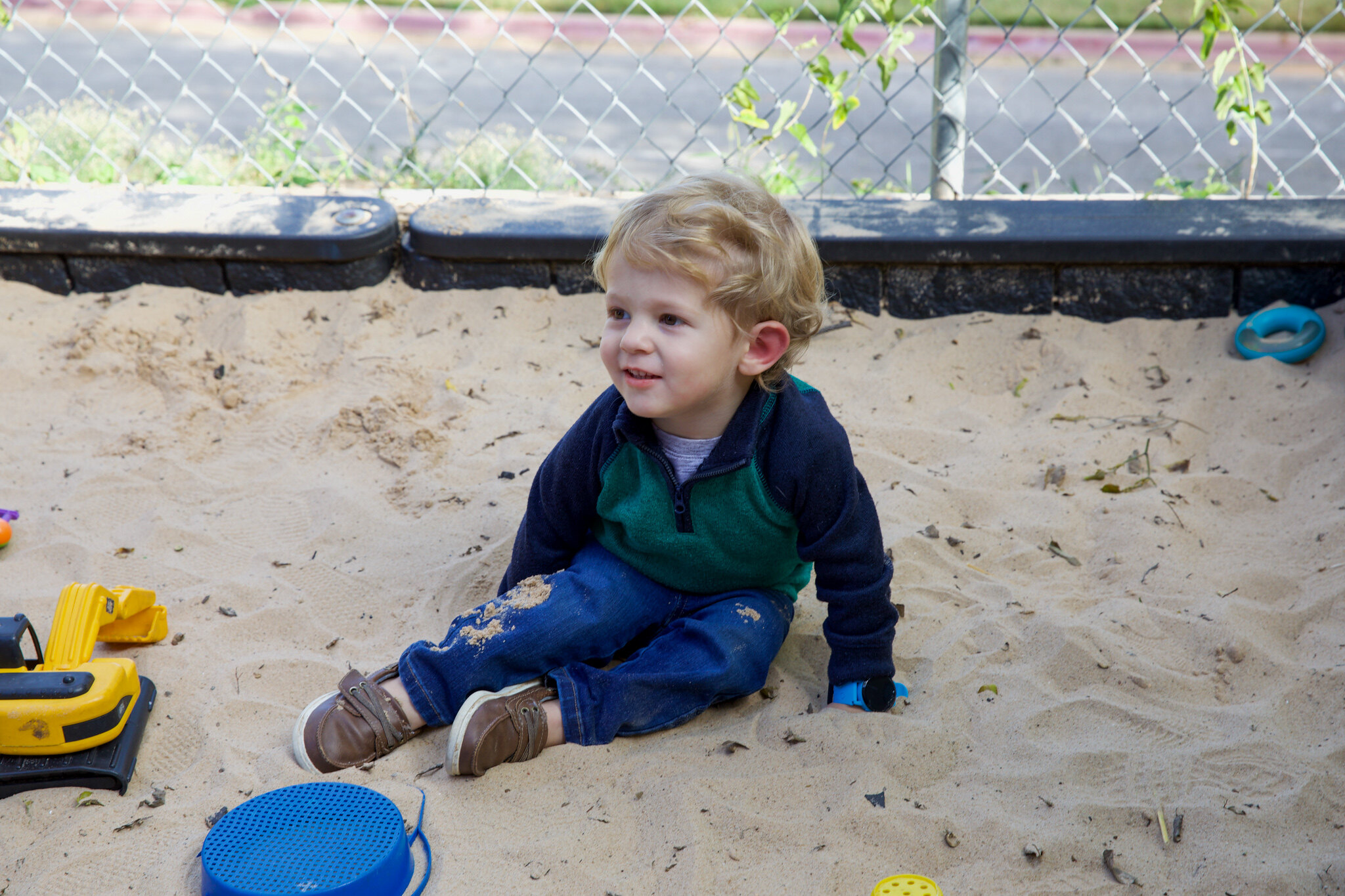 A kid plays in sand at school